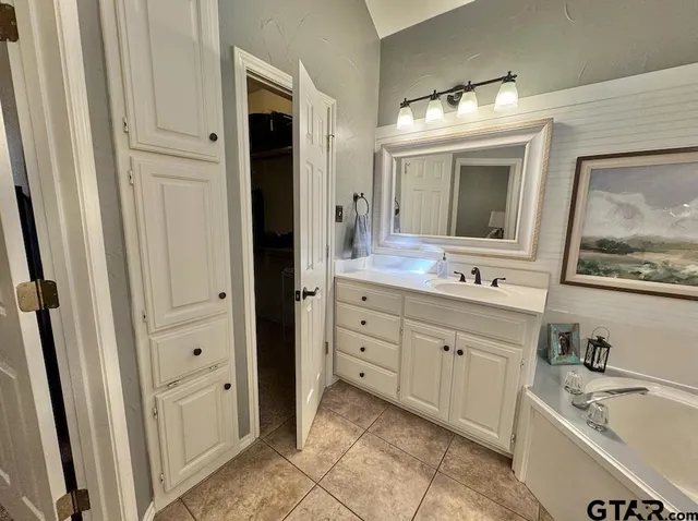 a spacious bathroom with a granite countertop sink mirror and bathtub
