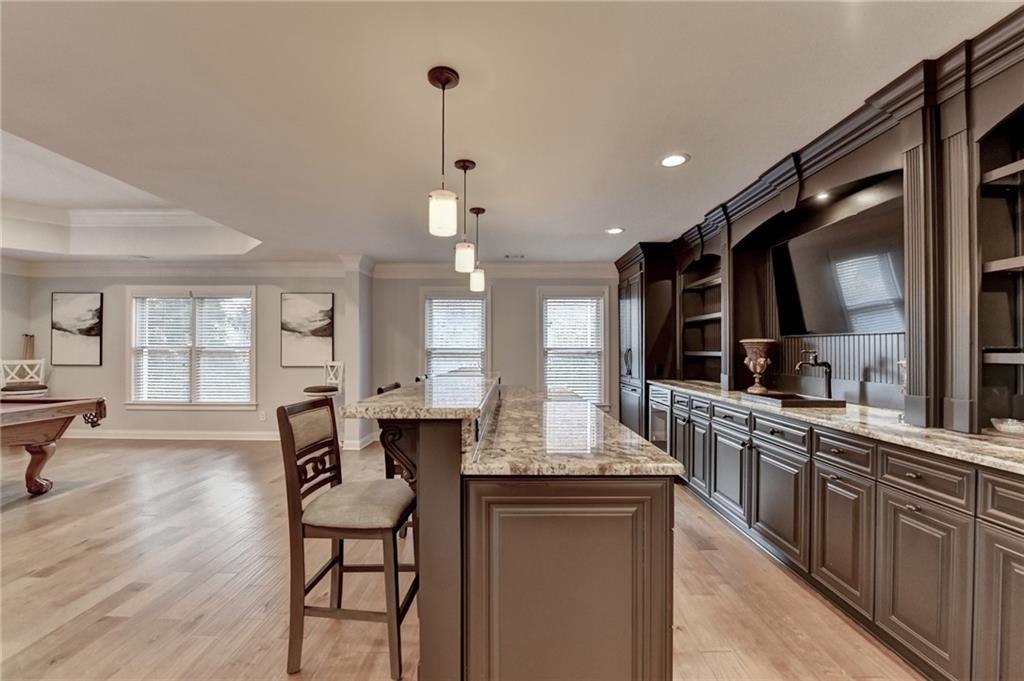 8360 Kenningston Way Duluth, GA 30097 - Photo 3 of 54 a kitchen with stainless steel appliances kitchen island granite countertop a table chairs in it and wooden floors