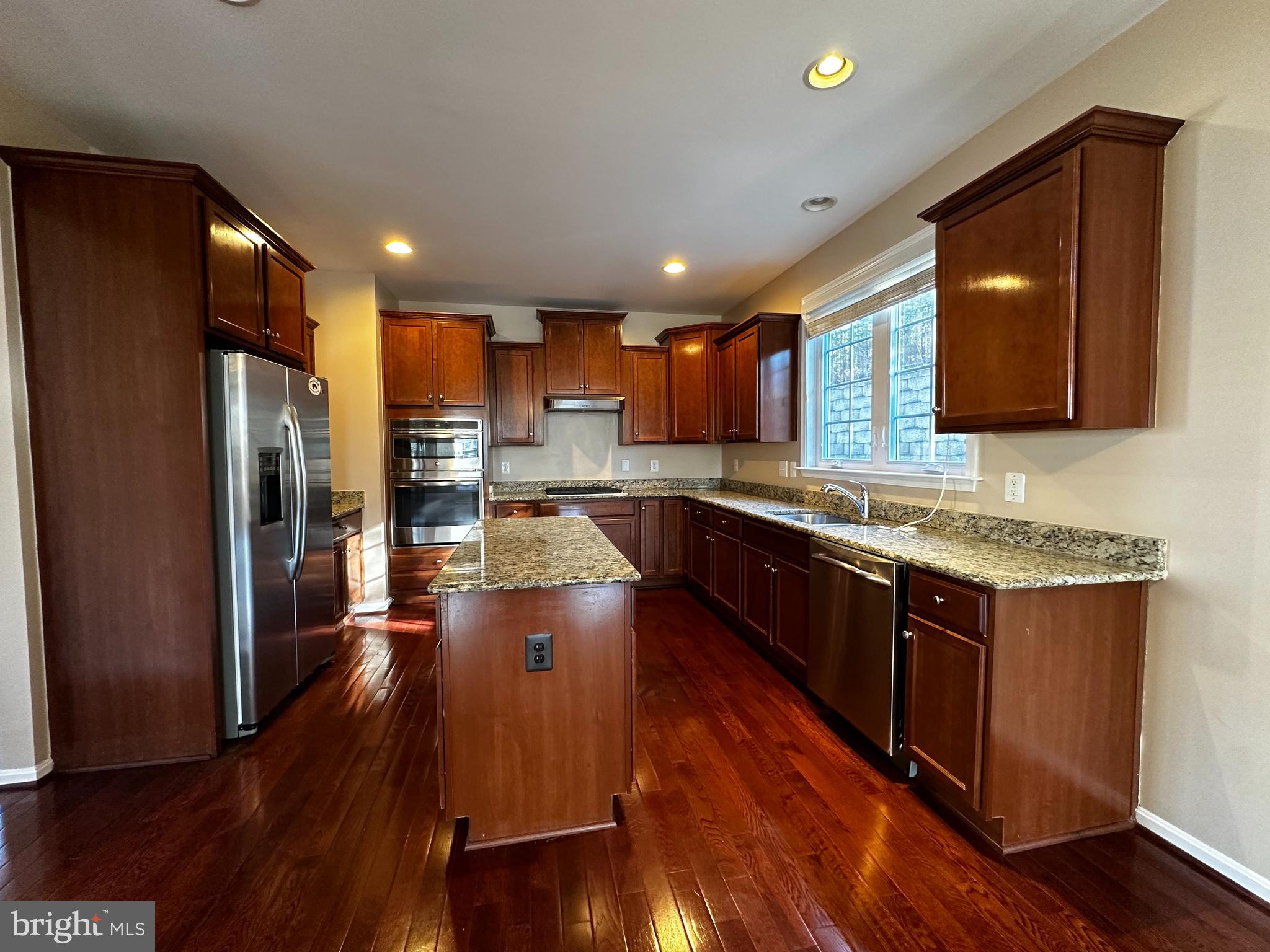 15165 Santander Drive Gainesville, VA 20155 - Photo 11 of 35 a large kitchen with stainless steel appliances granite countertop wooden floors a stove and a sink