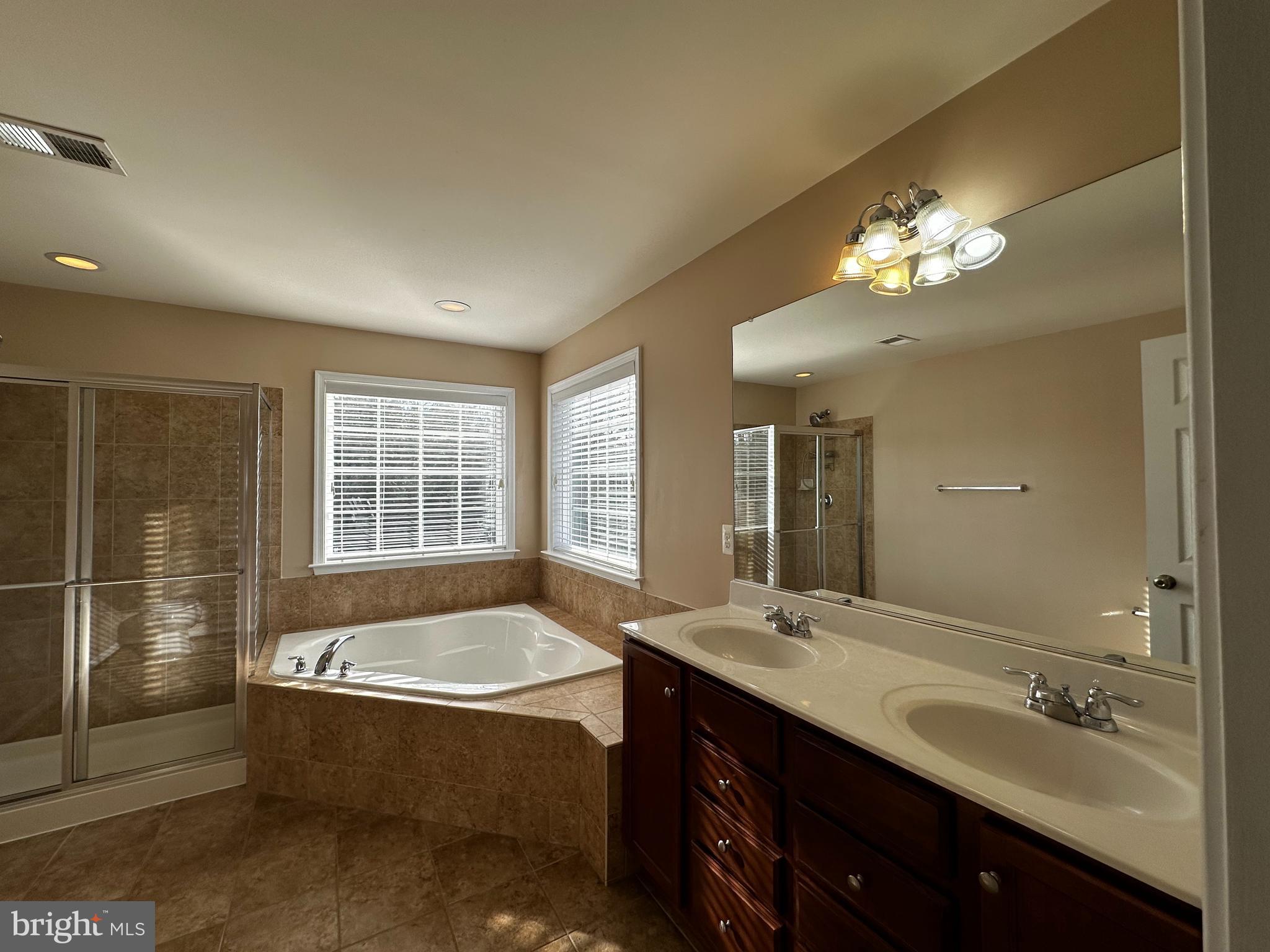 15165 Santander Drive Gainesville, VA 20155 - Photo 24 of 35 a spacious bathroom with a double vanity sink a large mirror and a bathtub