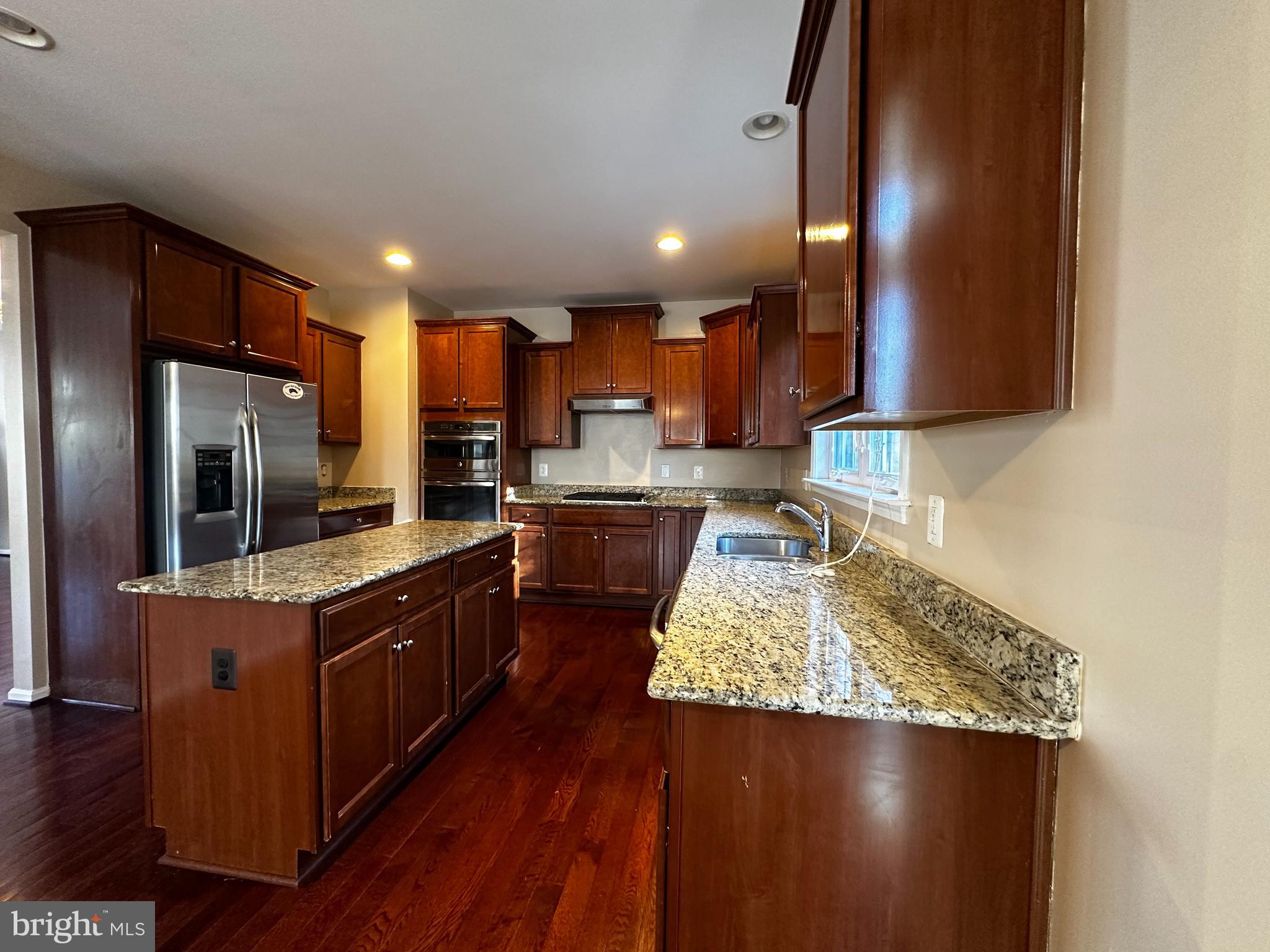15165 Santander Drive Gainesville, VA 20155 - Photo 10 of 35 a kitchen with kitchen island granite countertop wooden floors and stainless steel appliances
