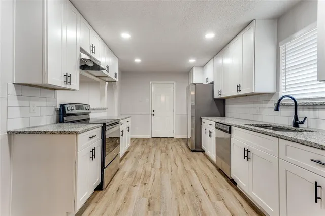 a kitchen with a sink a counter top space stainless steel appliances and cabinets