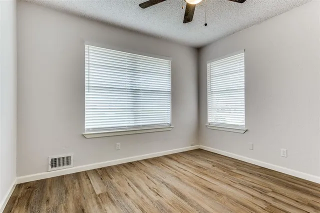 a view of an empty room with a window and wooden floor