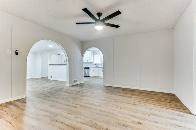 an empty room with wooden floor and ceiling fan