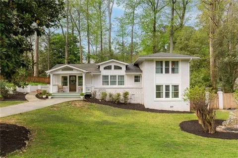 a front view of a house with a garden and trees