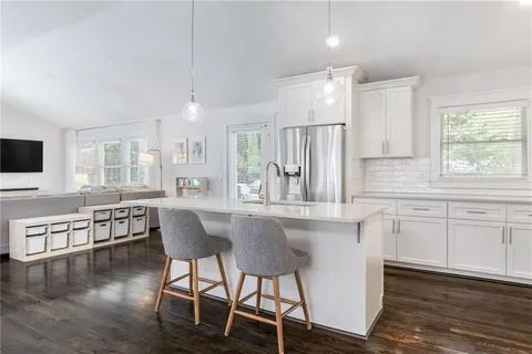 a kitchen with stainless steel appliances granite countertop a table chairs refrigerator and sink