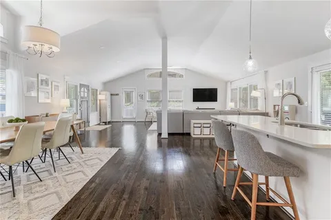 a dining room with wooden floor a chandelier a wooden table and chairs