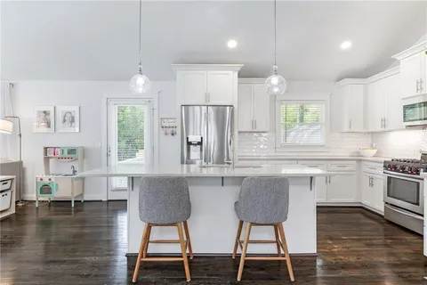 a kitchen with stainless steel appliances granite countertop a stove top oven a sink a dining table and chairs with wooden floor