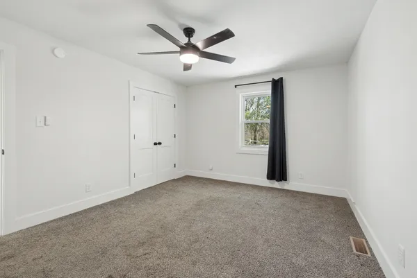 an empty room with window and ceiling fan
