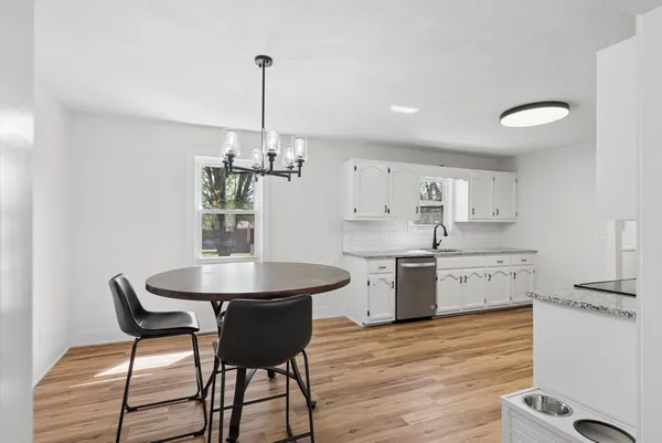 a kitchen with a table chairs and white cabinets