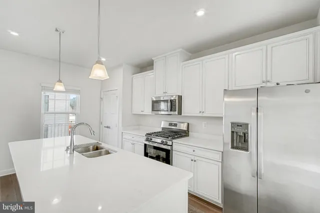 a kitchen with a refrigerator a sink and white cabinets