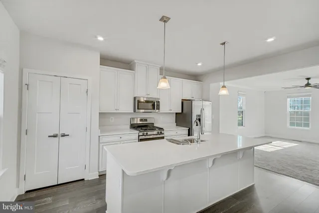 a kitchen with kitchen island a refrigerator a sink stainless steel appliances and cabinets
