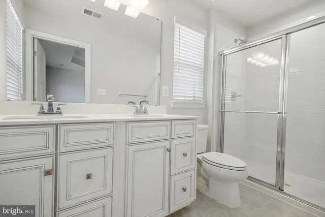 a bathroom with a shower sink vanity mirror and toilet