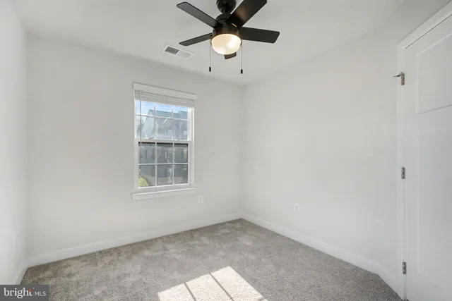 an empty room with a window and a fan