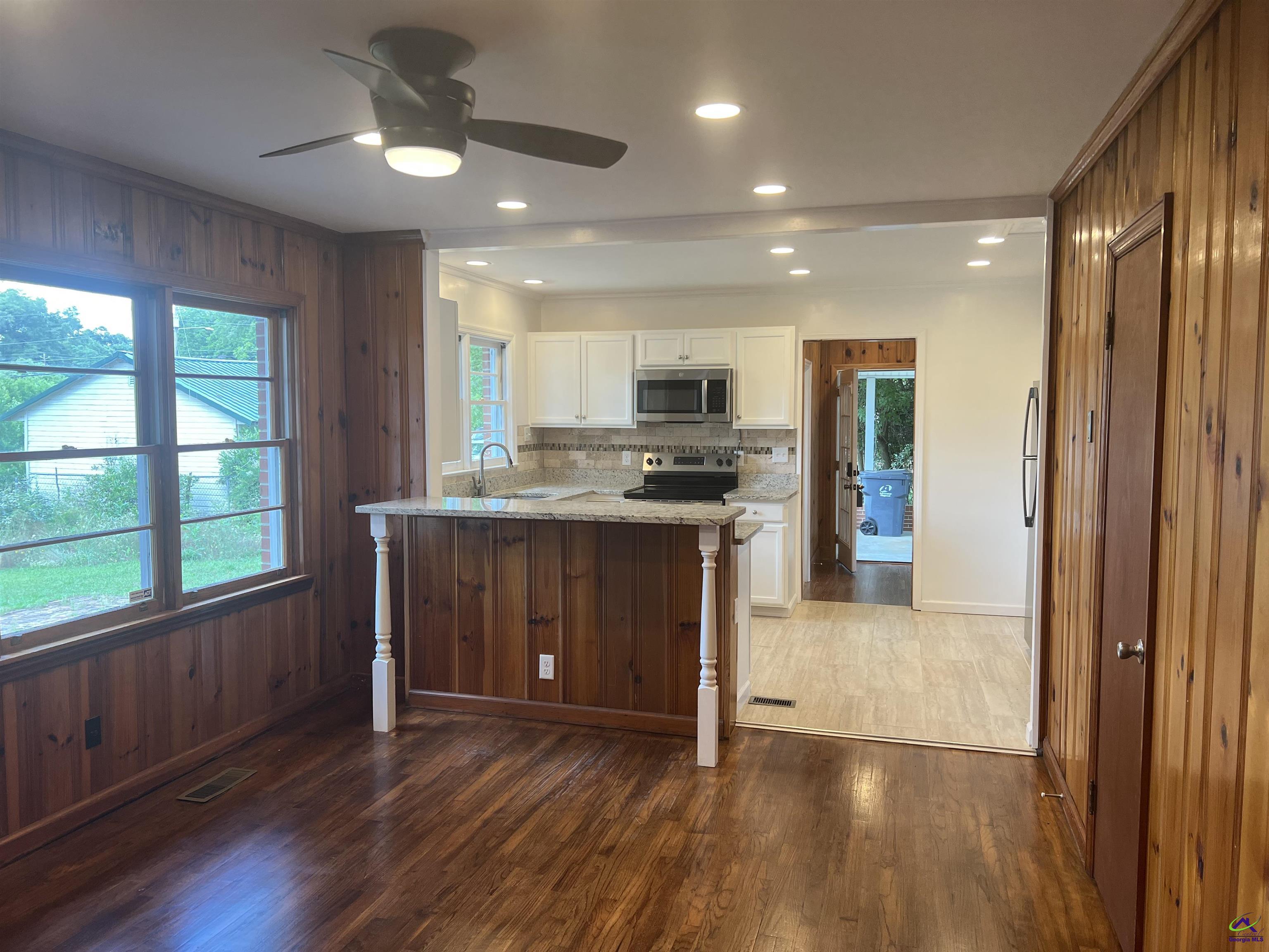 145 South 2nd Street Cochran, GA 31014 - Photo 9 of 24 a kitchen with kitchen island granite countertop wooden floors stainless steel appliances a sink and a large window