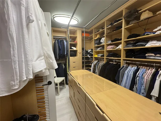 a view of walk in closet with clothes and shoes