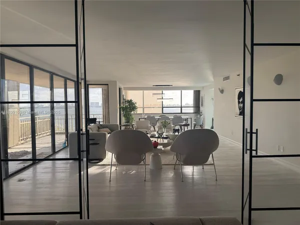 a living room with furniture floor to ceiling window and a refrigerator