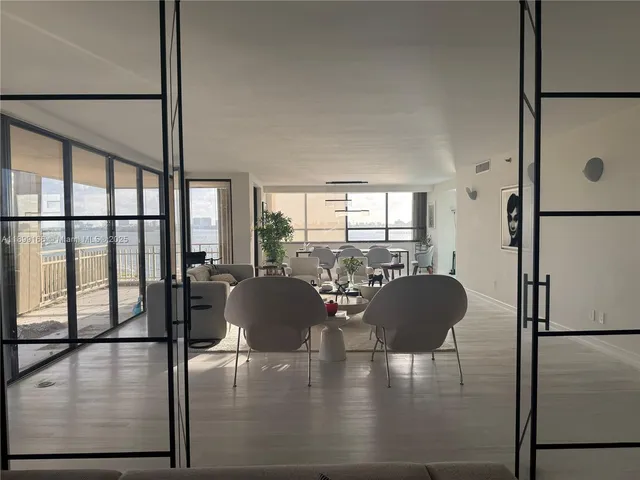 a living room with furniture floor to ceiling window and a refrigerator