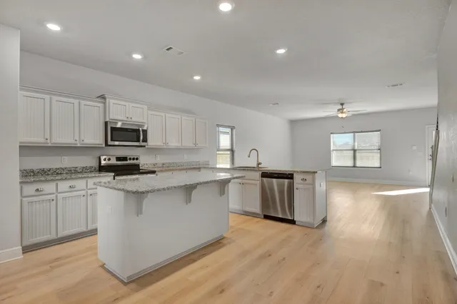 a kitchen with stainless steel appliances granite countertop a refrigerator a stove a sink and white cabinets