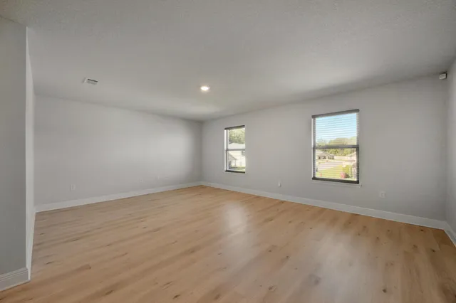 an empty room with windows and ceiling fan