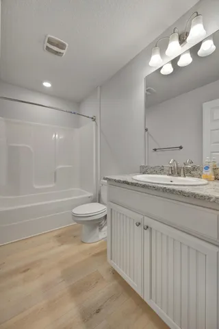 a bathroom with a granite countertop sink a toilet a large mirror and shower