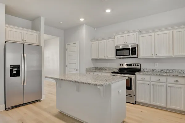a kitchen with stainless steel appliances granite countertop a refrigerator a stove a sink and white cabinets