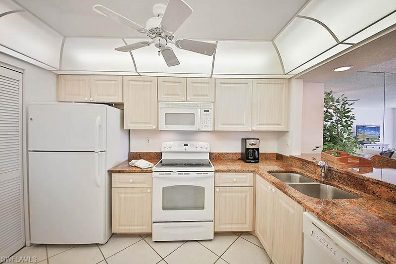 651 Seaview Court, Unit B207 Marco Island, FL 34145 - Photo 4 of 17 a white kitchen with granite countertop a sink a refrigerator a stove a washer dryer and cabinets