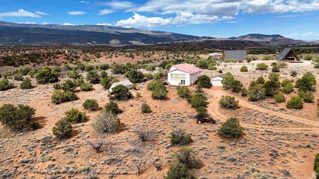 358 South Sky Drive Torrey, UT 84775 - Photo 6 of 82 Expansive desert landscape featuring a single-story residence with a red roof, multiple outbuildings, and natural vegetation
