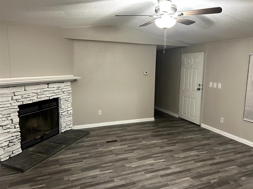 717 Byron Road Wilmer, TX 75172 - Photo 14 of 20 Living area featuring a stone-clad fireplace with hearth, wood-finish flooring, a ceiling fan with integrated lighting, and neutral wall tones
