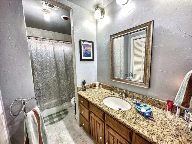 a bathroom with a granite countertop double vanity sink mirror and shower