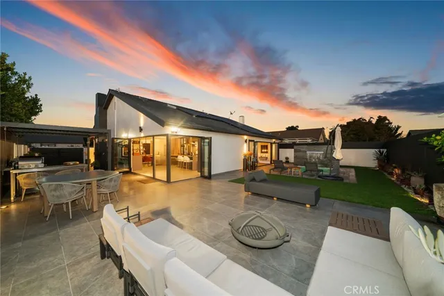 a view of a patio with couches table and chairs with plants and wooden fence
