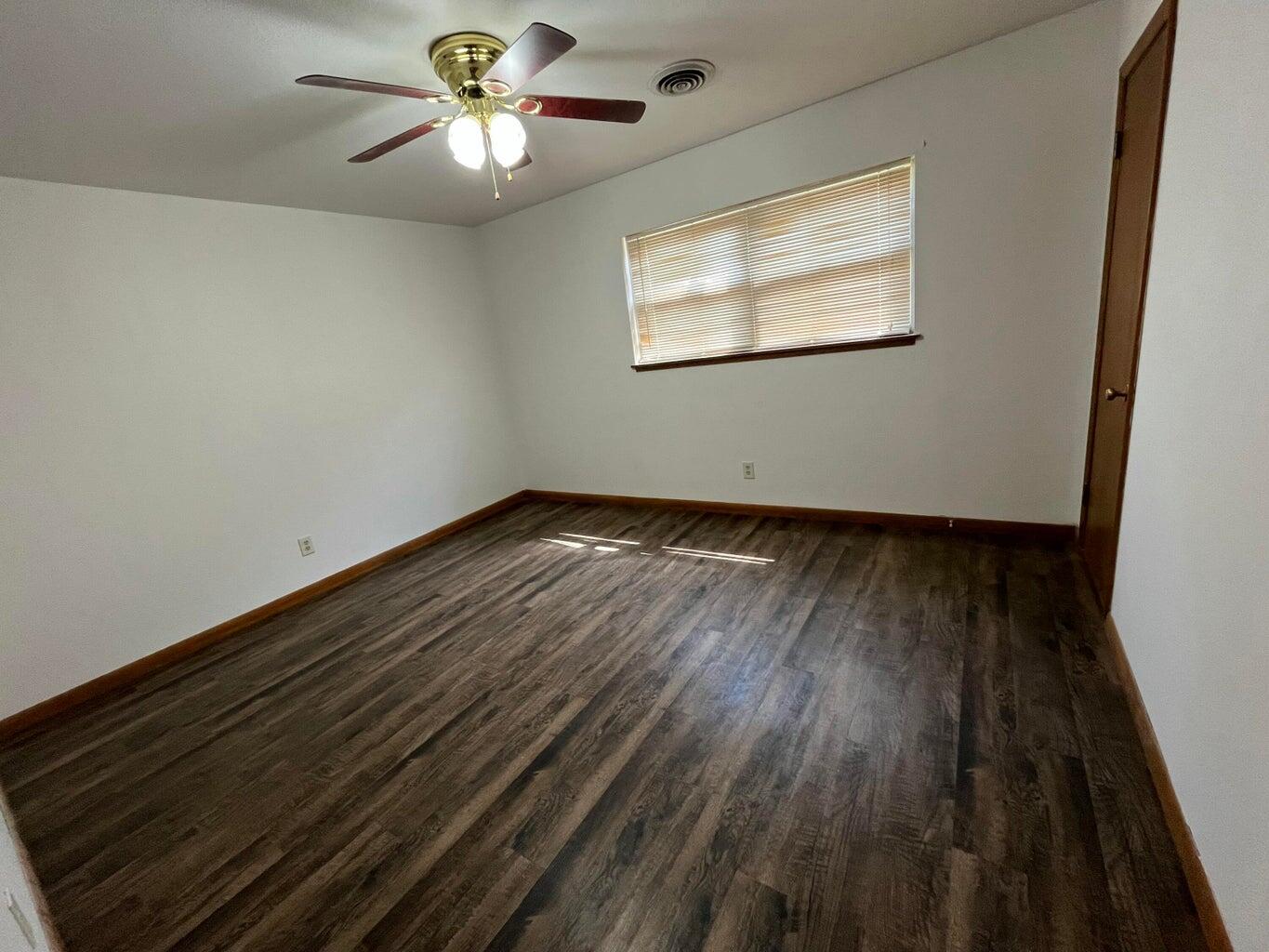 1307 Garland Plainview, TX 79072 - Photo 11 of 23 an empty room with wooden floor chandelier fan and windows