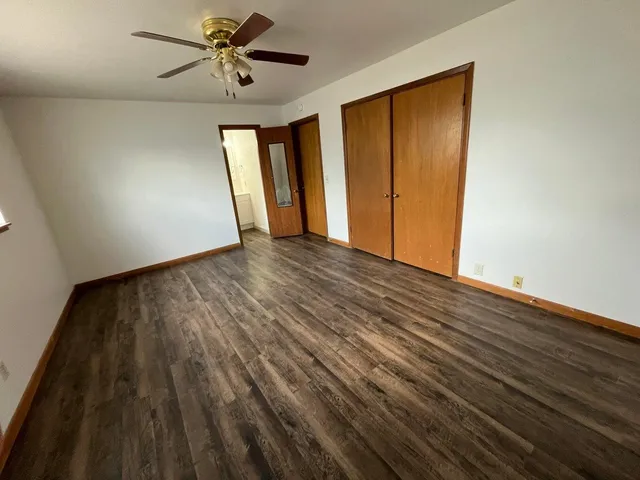a view of empty room with wooden floor and fan