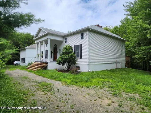 a backyard of a house with potted plants and large tree