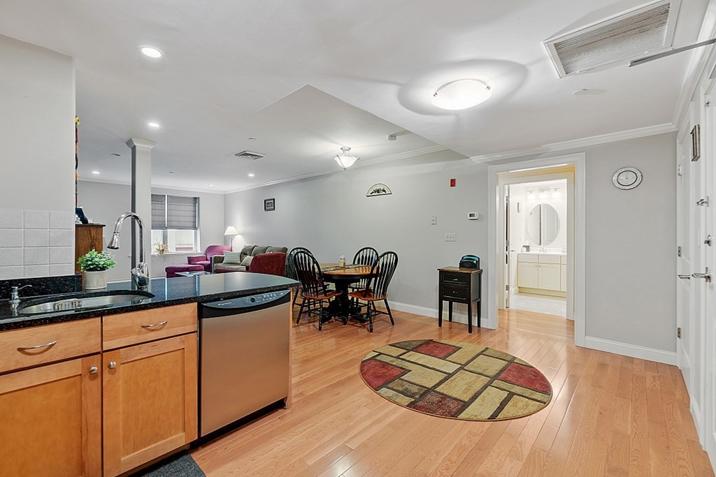 426 Main Street, Unit 205 Melrose, MA 02176 - Photo 10 of 26 a kitchen with stainless steel appliances granite countertop a refrigerator a sink a dining table and chairs with wooden floor