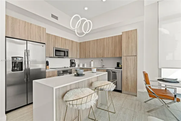 a kitchen with stainless steel appliances granite countertop a sink a stove a refrigerator cabinets and chairs