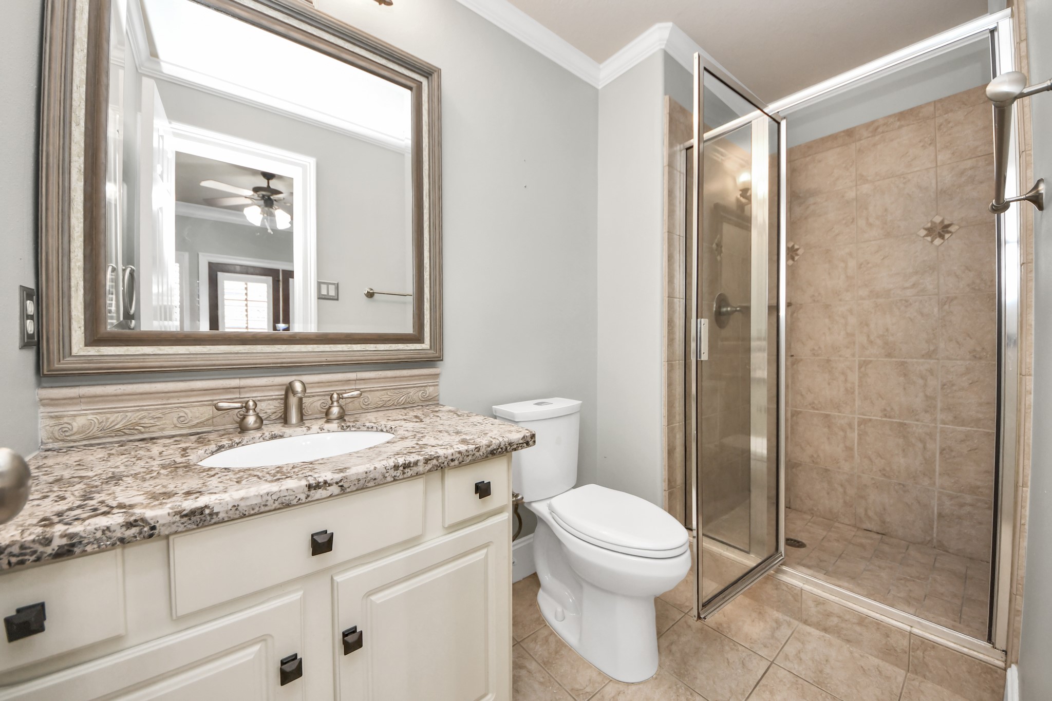 710 Jackson Hill Street Houston, TX 77007 - Photo 8 of 31 This Ensuite Bath on the first floor features a modern design with a granite countertop, undermount sink, and brushed nickel fixtures. It includes a spacious glass-enclosed shower with tile walls, a large framed mirror, and a neutral color palette for a clean, elegant look.