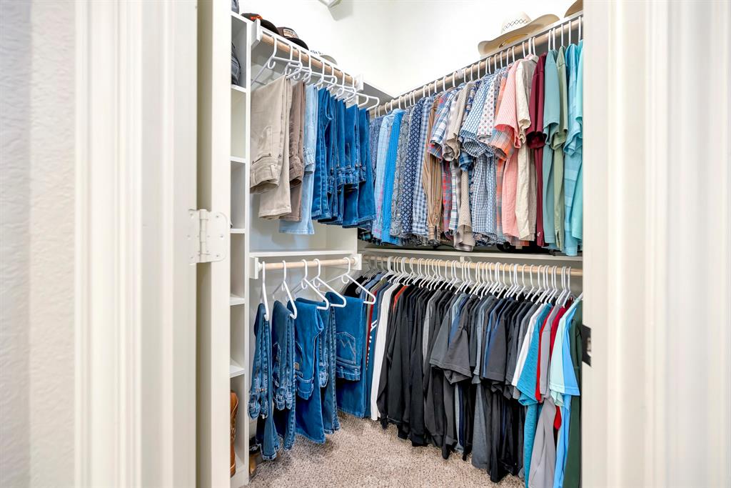 3224 North Cardinal Road Azle, TX 76020 - Photo 24 of 40 Walk-in closet with carpet flooring, white built-in shelving, multiple hanging rods, and an overhead light fixture