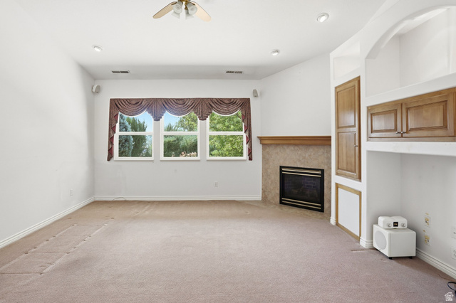 2190 750 West Perry, UT 84302 - Photo 11 of 42 Spacious room featuring a fireplace with a stone surround and wood mantel, built-in cabinetry, recessed lighting, and a ceiling fan