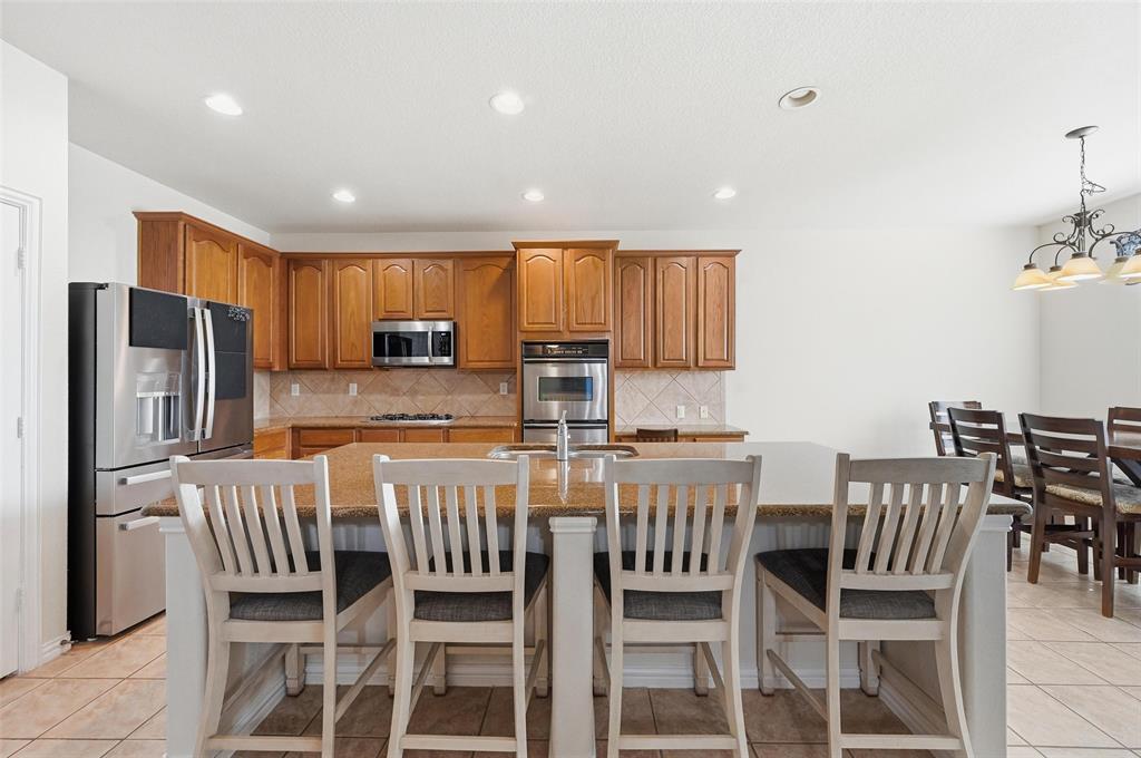 2319 Goshawk Street Grand Prairie, TX 75052 - Photo 11 of 40 a kitchen with stainless steel appliances granite countertop a stove a refrigerator a kitchen island and chairs