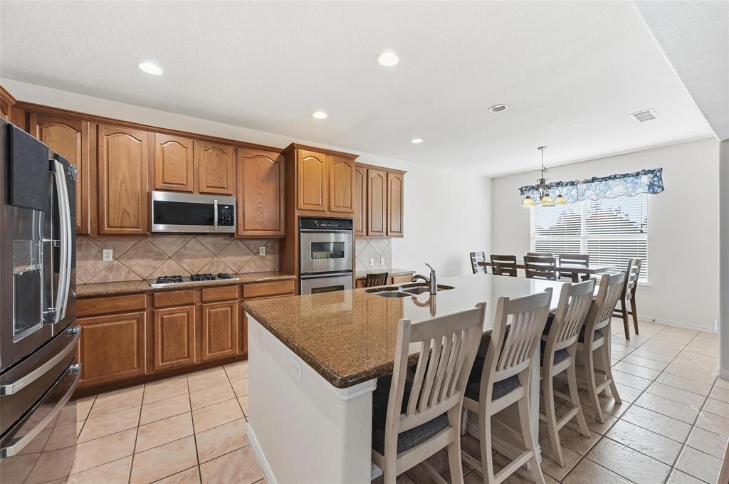 2319 Goshawk Street Grand Prairie, TX 75052 - Photo 12 of 40 a kitchen with stainless steel appliances granite countertop a stove top oven a sink dishwasher a dining table and chairs