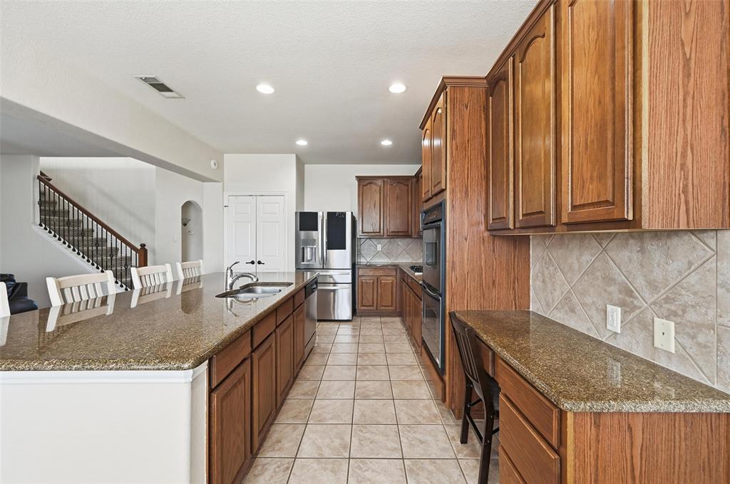 2319 Goshawk Street Grand Prairie, TX 75052 - Photo 13 of 40 a kitchen with stainless steel appliances granite countertop a sink and cabinets