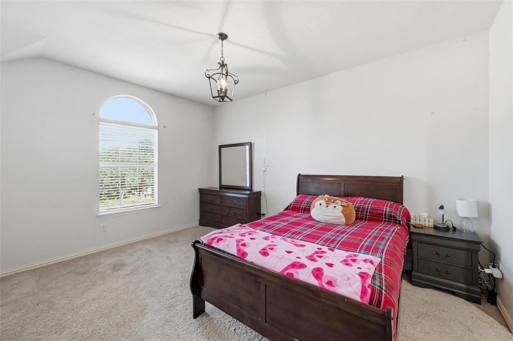 2319 Goshawk Street Grand Prairie, TX 75052 - Photo 30 of 40 a bedroom with a bed a dresser and a chandelier