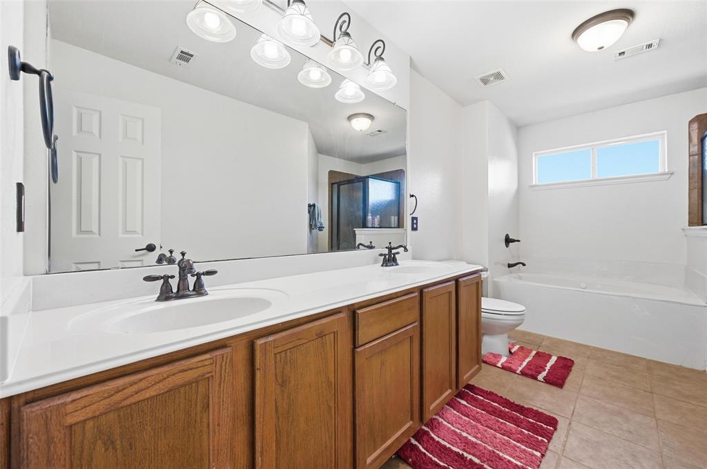 2319 Goshawk Street Grand Prairie, TX 75052 - Photo 34 of 40 a bathroom with a sink a large mirror and a bathtub