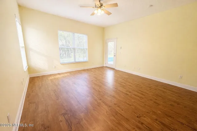 an empty room with wooden floor and windows