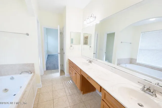 a spacious bathroom with a tub sink and mirror