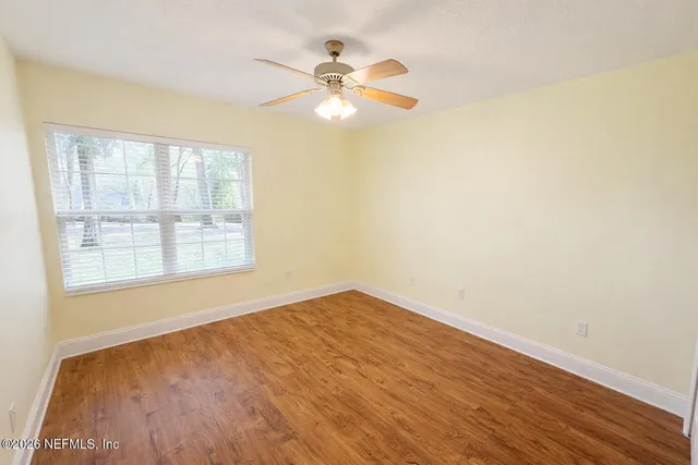 an empty room with a window and a ceiling fan