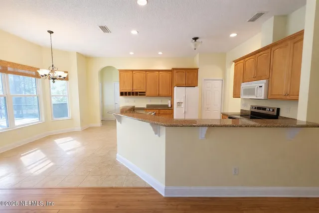 a kitchen with stainless steel appliances granite countertop a stove a sink a refrigerator and white cabinets with wooden floor