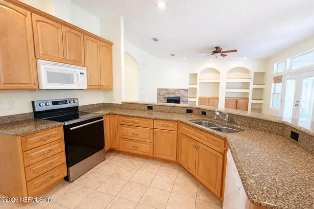 a large kitchen with stainless steel appliances granite countertop a stove sink and cabinets
