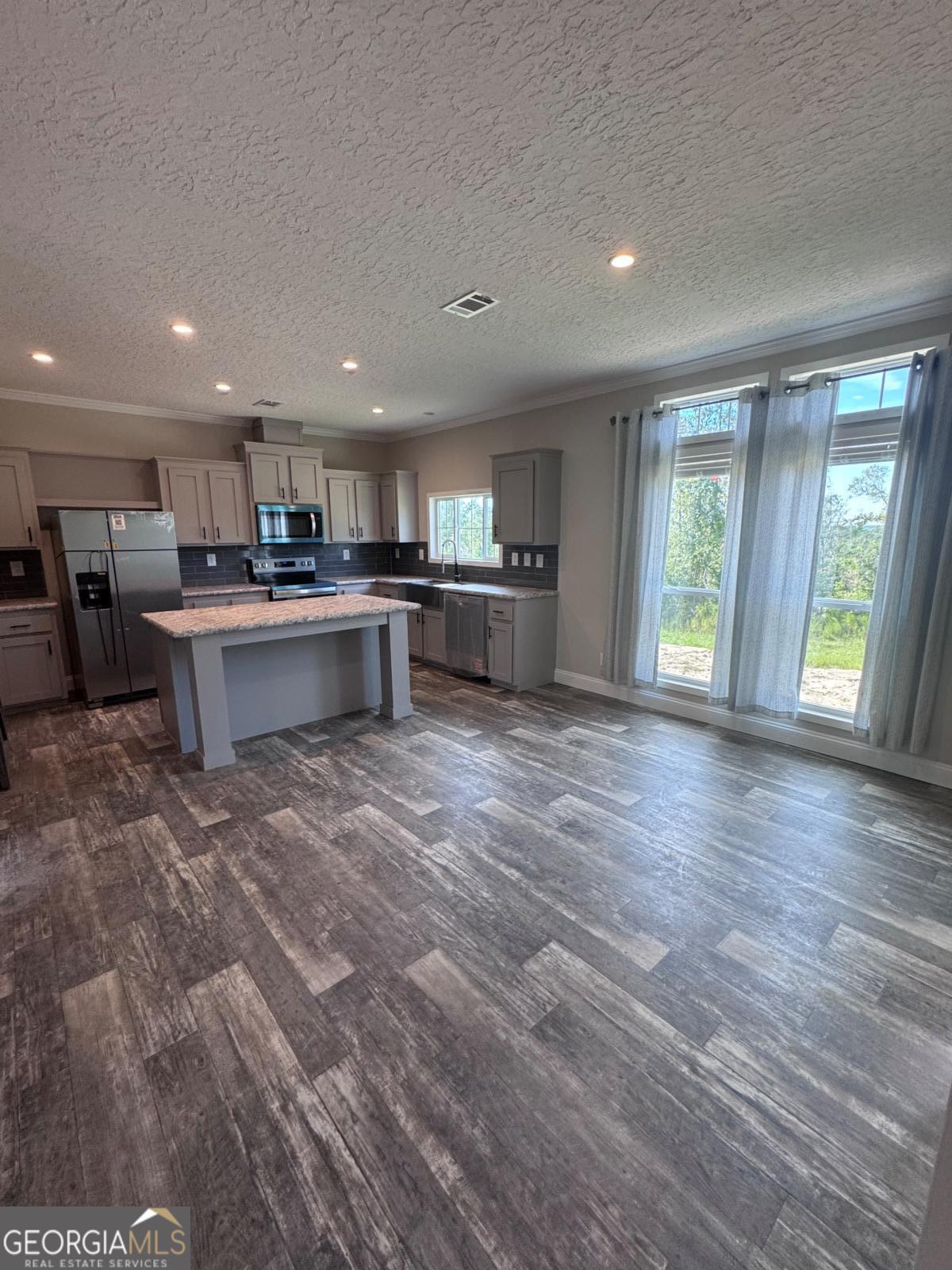 44 Long Leaf Road Hazlehurst, GA 31539 - Photo 13 of 21 a large kitchen with kitchen island a stove a sink dishwasher and a dining table with wooden floor
